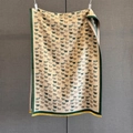 Dettaglio ravvicinato di una sciarpa in maglia con motivi di mucca e nappe gialle fini - Bordo Verde (GSJ-234-Bordo Verde)