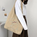 Khaki fluffy fleece tote bag with blue dog embroidery shown on model shoulder - Tilting Head Dog / Brown