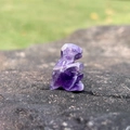 Miniature amethyst dinosaur figurine carved from natural purple crystal on stone - Amethyst