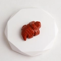 Hand-carved red jasper gemstone alligator figurine displayed on a white geometric stand - Red Jasper