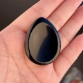 Polished black obsidian palm stone in teardrop shape for thumb massage and therapy - Obsidian