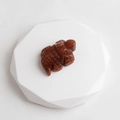 Hand-carved red sandstone hippopotamus figurine with natural mineral texture on white stand - Purple Aventurine