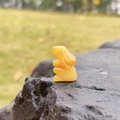 Hand-carved yellow gemstone rabbit figurine shown on a natural rock surface - Topaz