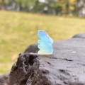 Cute opal glass rabbit figurine in translucent blue, displayed on a natural rock - Synthetic Opal