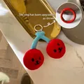 Roter und blauer Kirsch-Plüsch-Schlüsselanhänger mit Gesichtern auf Marmorboden - Roter Kirsch-Emoji-Anhänger