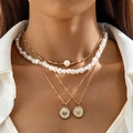 Detail of layered gold necklaces with faux pearls, seashell and starfish charms on a white shirt - Four-Layer Pearl Starfish Relief (30667-nek-G)