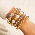 Détail de bracelets superposés en perles d'or et d'argent avec de grandes perles blanches - Style Perle Mélangé Or Argent (28517-G)