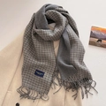 Detail of grey houndstooth scarf with fringe edge and label on ivory wool coat - Black and Gray