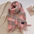 Detail eines rosa-grau karierten Schals mit Fransen auf einem Wollmantel mit Requisiten - Rosa