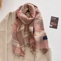 Close-up of soft plaid scarf with fringe detail and brand label on a wool coat - Pink