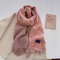 Schal mit rosa-grauem Karomuster und Fransen, elegant auf beigem Wollmantel drapiert - Rosa