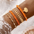 Detail of bohemian stackable bracelets featuring shells, orange beads and gold leaf charms - Orange