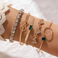 Five-piece gold layered bracelet set with heart charms and green gemstones worn on wrist - 5-Piece Heart Emerald Style (25775-gold)