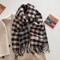 Detailed view of soft cashmere-like texture and tassel edges on the plaid winter scarf - Black