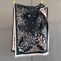 Dettaglio dei motivi floreali jacquard sulla sciarpa nera con frange eleganti - Nero