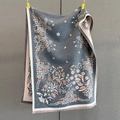 Detailed close-up of thick floral cashmere scarf with elegant tassels and flower patterns - Gray