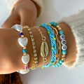 Primer plano de cinco pulseras bohemias apilables con conchas y perlas en la muñeca - Estilo Multicapa Dorado (26346-gold)