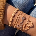 Gold tone 4-piece bracelet set with Love charms and interlocking hearts on female wrist - Interlocking Heart And Love Letter Four Piece Gold Bracelet Set (25717-gold)