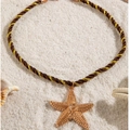 Detailaufnahme eines goldenen Seestern-Anhängers auf geflochtener Kordel im Sand - Seestern(26700-color brown) / Braun