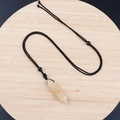 Natural light yellow gemstone hexagonal pendant with black woven rope on wooden tray - Yellow Jade With Cord