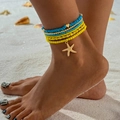 Detail van gelaagde blauwe en gele kralen enkelbandjes met een zeester op het strand - Geel Blauw Hart Zeester Stijl (27141-yellow)