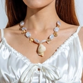 Bohemian pearl necklace with sea snail shell pendant worn on a model's neck - White Irregular Pearl Gold Conch Tag (29926-G white)