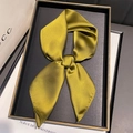 Detail of olive green silk scarf with metallic sheen on an elegant black display tray - Yellow