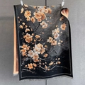 Detail der orangefarbenen Blumenmuster auf einem schwarzen Kaschmir-ähnlichen Schal - 190*65cm / Schwarzbraun