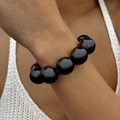 Detail of high-gloss black oversized beads on a minimalist ethnic style stretch bracelet - Black