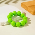 Macro view of neon green acrylic beaded bracelet on a white textured stone tray - Fluorescent Green