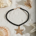Starfish pendant necklace with black cord and gold finish on a white sandy beach background - Starfish(26700-black)
