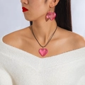 Close-up of pink resin heart pendant necklace and matching earrings on a model - Pink