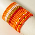 Detail of colorful multi-layered bohemian beaded bracelets on a display stand - Orange/Red/Yellow/White Warm Tones (31013-bra-ora-EP)