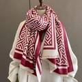 Detail van rood-beige sjaal met geometrisch patroon en franjes op een witte jas - Rood