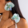 Detailed close-up of large mint green orchid flower accessory worn as a hair clip by a model - Gradient Blue Green (27335-4-Light Green)