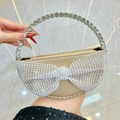 Golden crescent evening bag featuring a large rhinestone bow and crystal ring handle - Gold