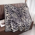 Dettaglio di una sciarpa leopardata classica su un divano in pelle, tessuto morbido - Leopardo Classico (HSM-63) / Nero