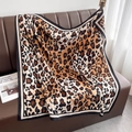 Dettaglio di una sciarpa di seta leopardata drappeggiata su un divano con luce soffusa - Leopardo Classico (HSM-63) / Marrone
