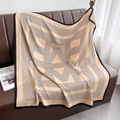 Détail d'une grande écharpe beige en maille avec motifs géométriques noirs sur cuir - 90x90cm / Chameau Clair