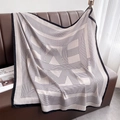 Détail d'une écharpe légère à rayures drapée sur un canapé montrant la texture du tissu - 90x90cm / Blanc clair
