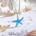 Detailaufnahme des blauen Seestern-Anhängers mit Kordel auf Muscheln im Strand-Stil - Blau