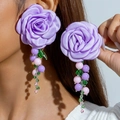 Detail von lila Satin-Rosenohrringen mit bunten Perlenquasten und grünen Blattakzenten - Lila