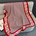 Dettaglio di uno scialle in seta a motivi geometrici rossi su un divano grigio - Grande Lungo / Rosso (F-456)