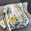 Detailed texture of printed silk scarf with yellow lilies and dark green border on sofa - Green Trim