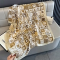 Detailed close-up of geometric pattern silk scarf draped on a luxury grey leather sofa - White Trim