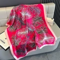 Detail of rose red feather print silk scarf draped on a grey leather background - Pink