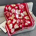 Detailaufnahme des roten Seidenschals mit Blumenmuster auf grauem Ledersofa - Rot