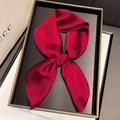Elegant dark red satin silk scarf tied in a bow shape on a luxury display tray - Burgundy