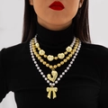 Vista detallada de un collar multicapa de perlas doradas con colgantes de lazo y corazón - Estilo en Capas de Perla con Lazo (28261-gold)