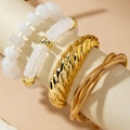 Detail of four-piece gold metal bracelet set with white beads on a warm display stand - Modern Minimalist Twisted Cuff 4-Piece Set (31124-bra-G-EP)